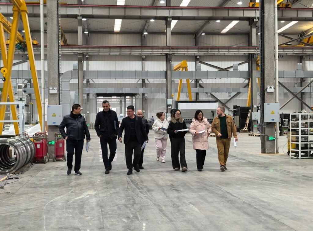 Customers and service staff reviewing pellet machinery inside a manufacturing facility