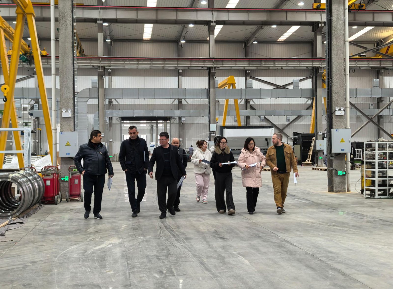 Customers and service staff reviewing pellet machinery inside a manufacturing facility